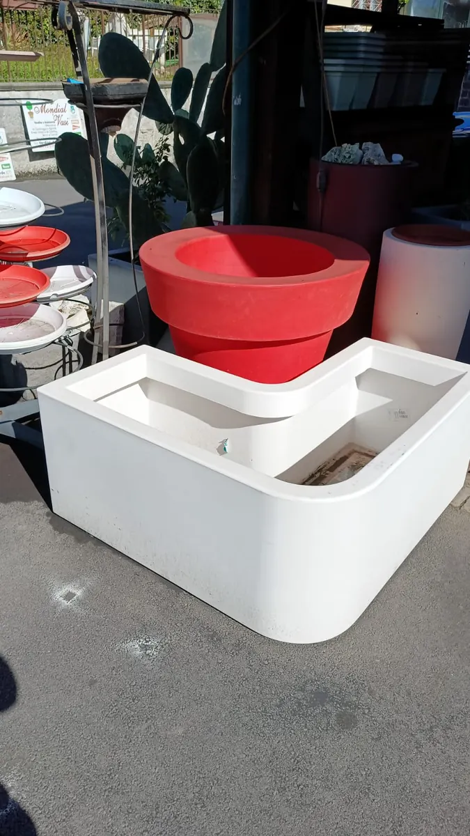 Un vaso rosso e una fioriera bianca ad angolo in resina