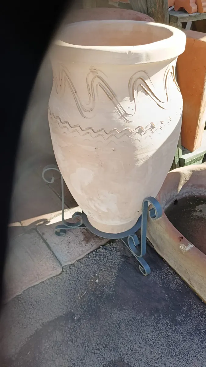 Una giara siciliana in terracotta chiara sul suo supporto in ferro