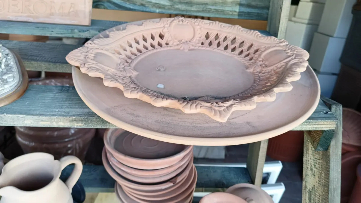 Un sottovaso in terracotta traforata sullo scaffale