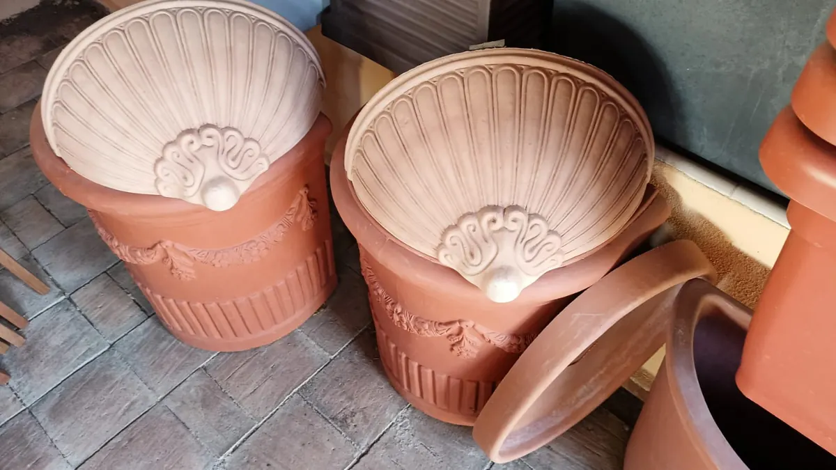 Due vasi a conchiglia in terracotta con i festoni, esposti in negozio